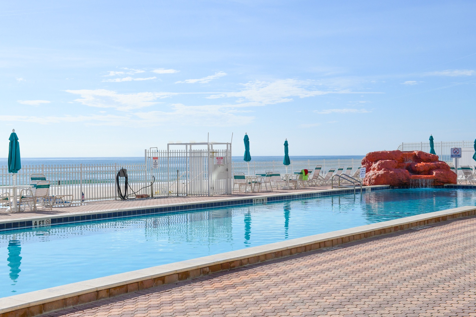 The sparkling outdoor pool offers direct views of the ocean, complete with a waterslide feature and plenty of lounge chairs for relaxation under the coastal sun.