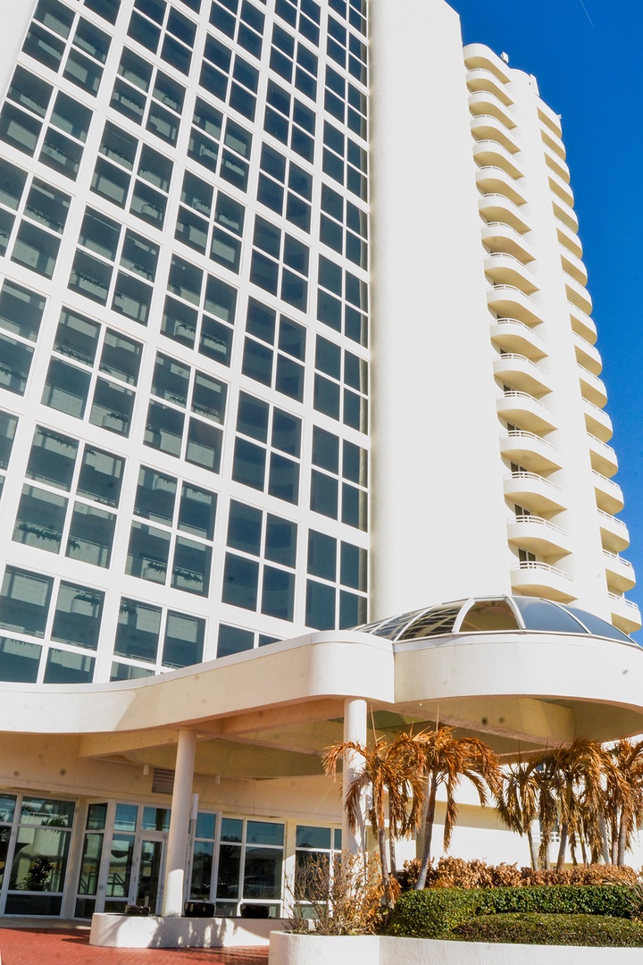 Modern beachfront towers rise majestically against clear blue skies, with tropical palms enhancing the coastal resort atmosphere at arrival.