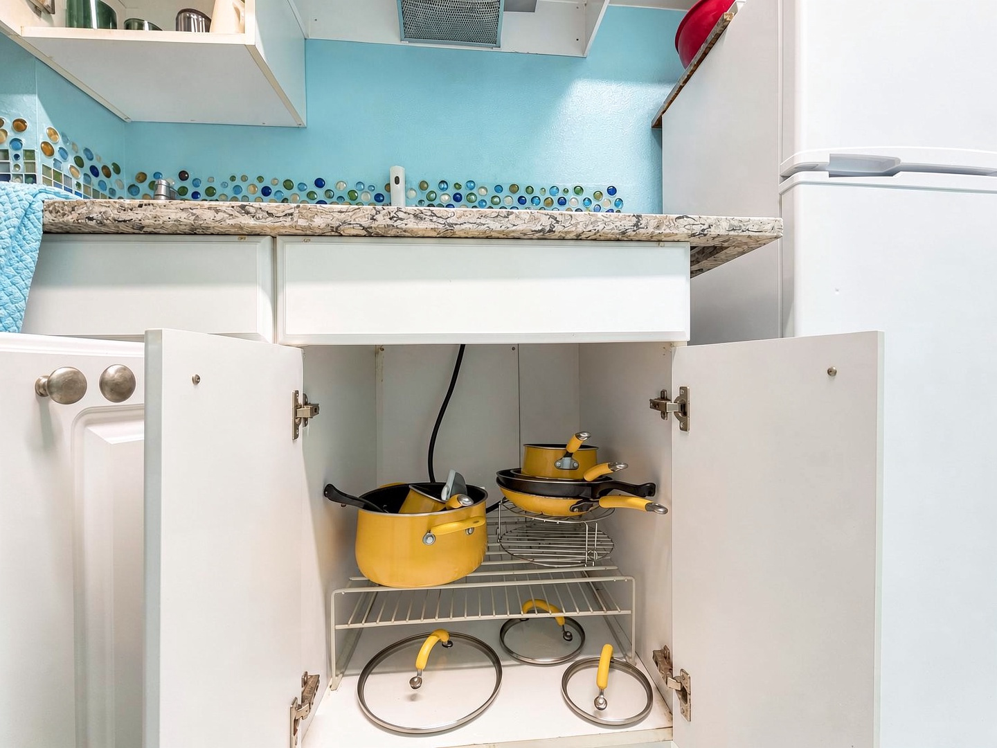 Your fully equipped kitchen features vibrant yellow cookware and organized storage beneath gorgeous granite countertops, making meal prep feel like home.