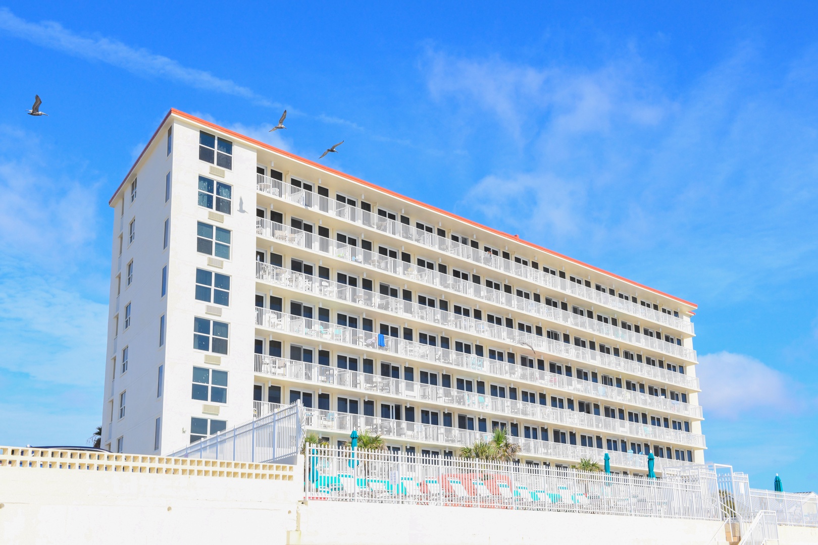 This beachfront property offers direct access to pristine white sand and stunning ocean views. The multi-story building features private balconies and a refreshing pool area, providing the perfect coastal retreat.