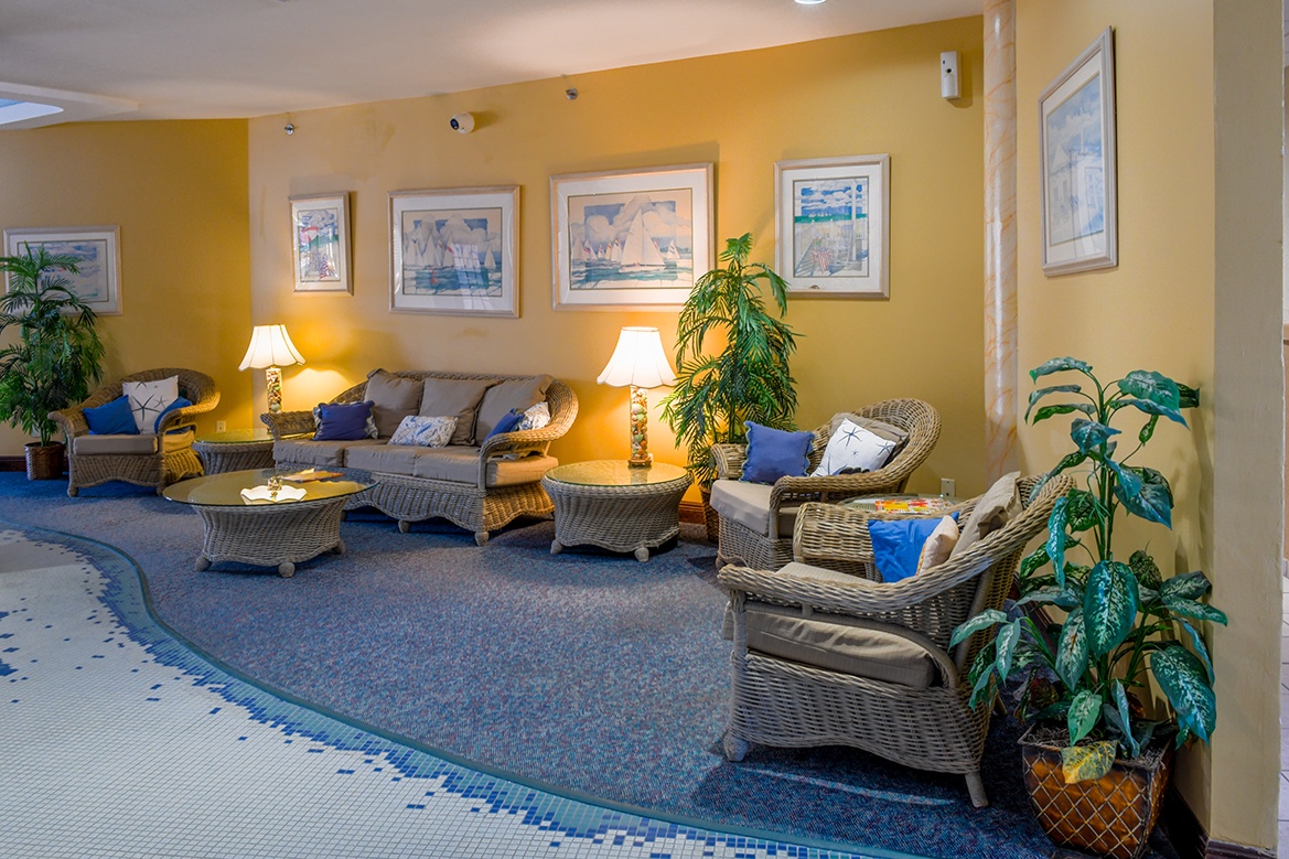 Unwind in this elegant communal lounge with plush wicker seating, warm lighting, and tropical plants creating your perfect relaxation retreat.