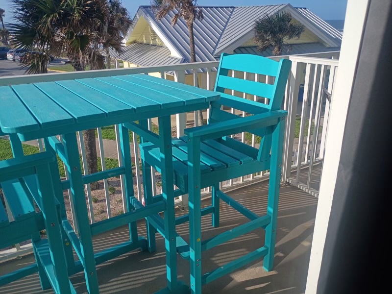 Another view of your private balcony features bright turquoise seating perfect for morning coffee or evening cocktails. Just beyond, inviting you to explore the beach just steps away.