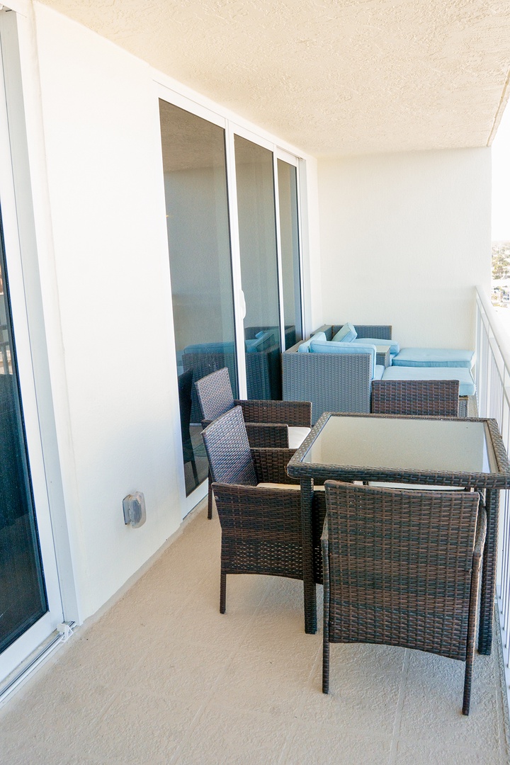 Your private balcony awaits with comfortable wicker dining set and cozy lounge seating—perfect for morning coffee or evening relaxation.