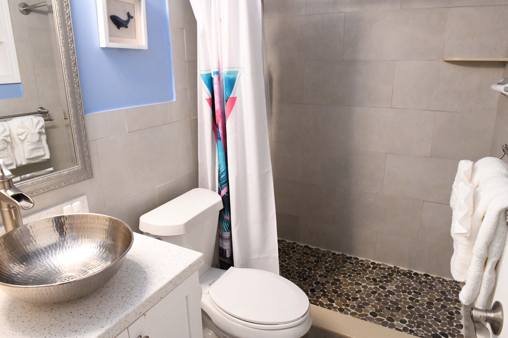 Step into your spa-inspired bathroom, where warm gray tiles and a hammered-metal sink create a serene escape. Soft towels await, and the pebbled shower floor adds natural texture to your daily routine.