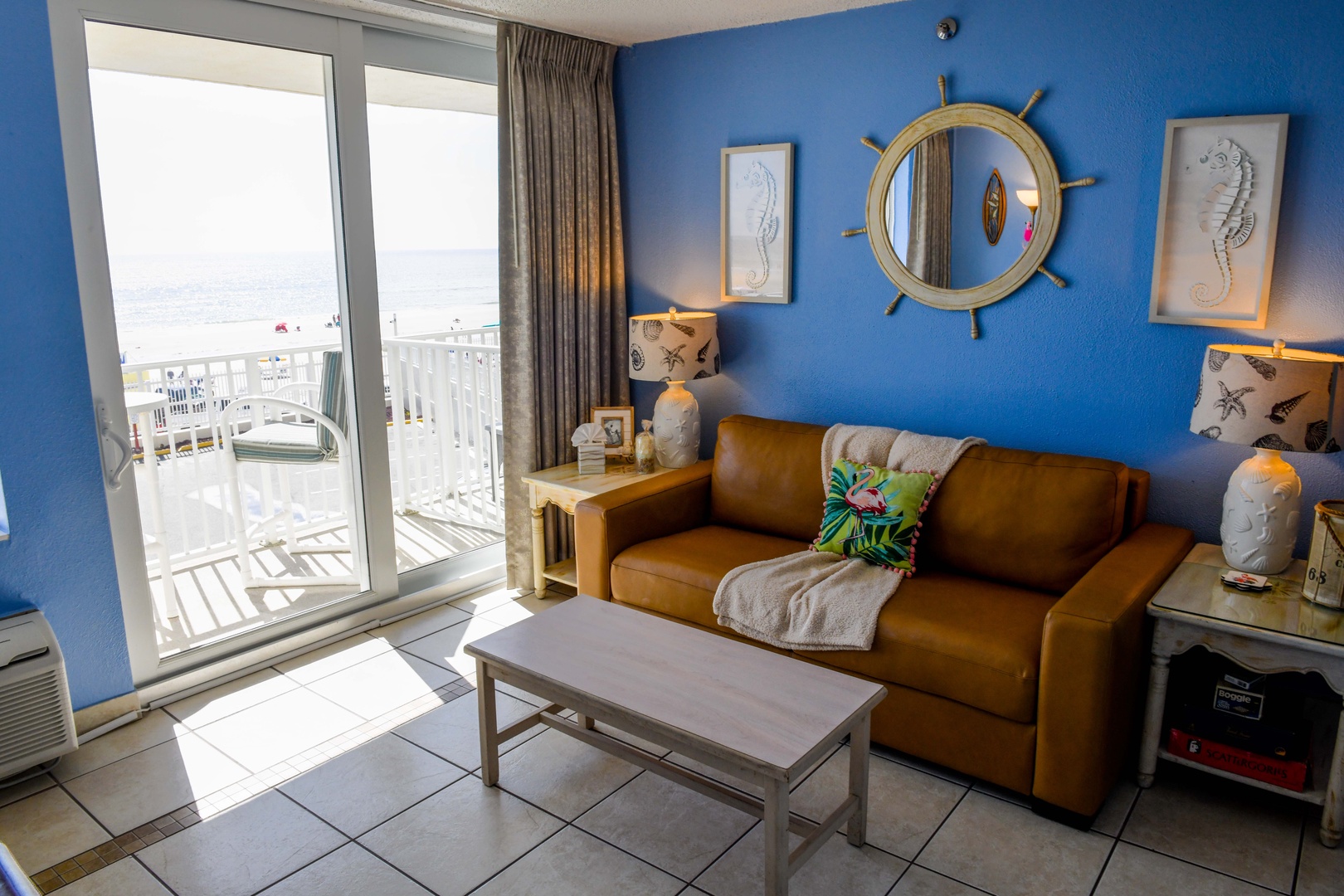 Step into your coastal retreat with a nautical-inspired living space featuring a plush leather sofa and charming maritime décor, then open the balcony doors to let in refreshing ocean breezes.