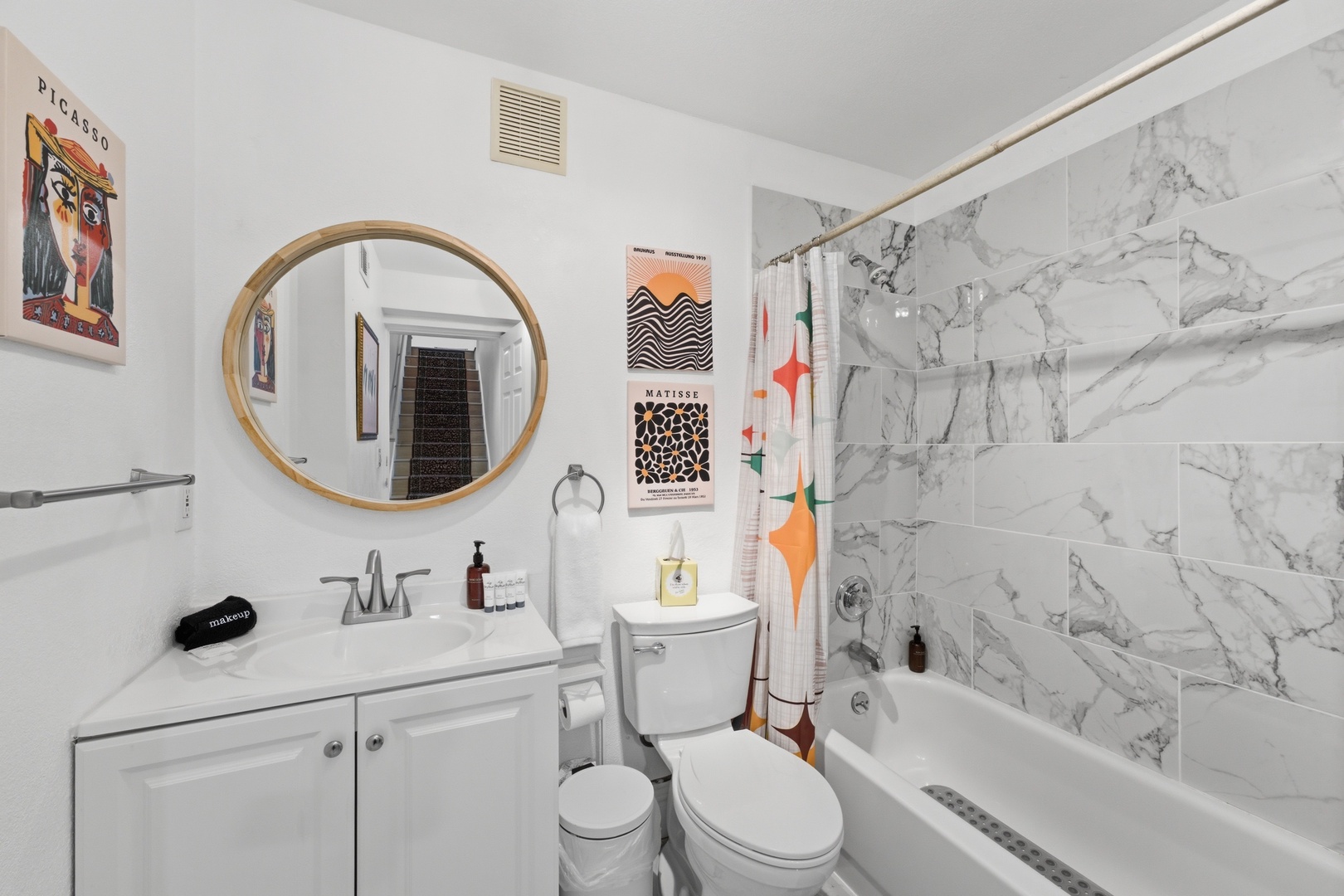 Step into a bright, artfully decorated bathroom with elegant marble tile shower, modern fixtures, and curated art touches. Pamper yourself in this stylish space designed for your comfort.