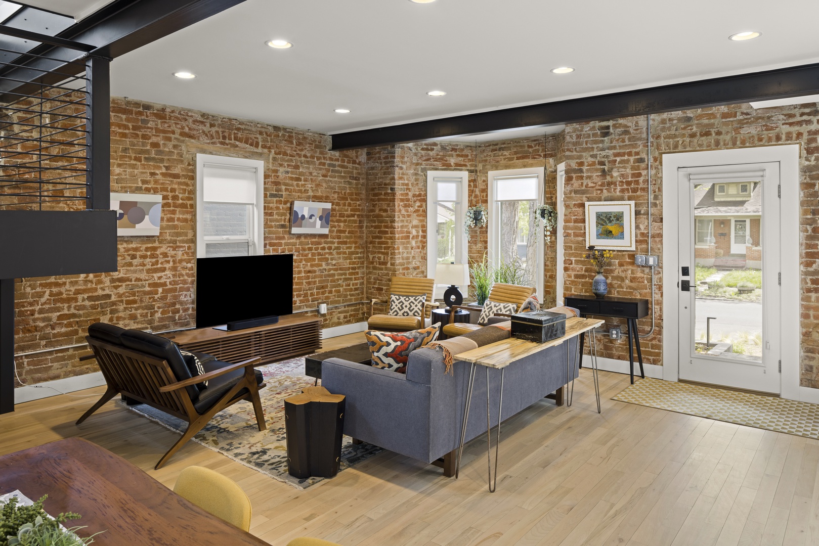 Unwind in your stylish living space featuring exposed brick walls, modern furnishings, and natural light streaming through large windows.