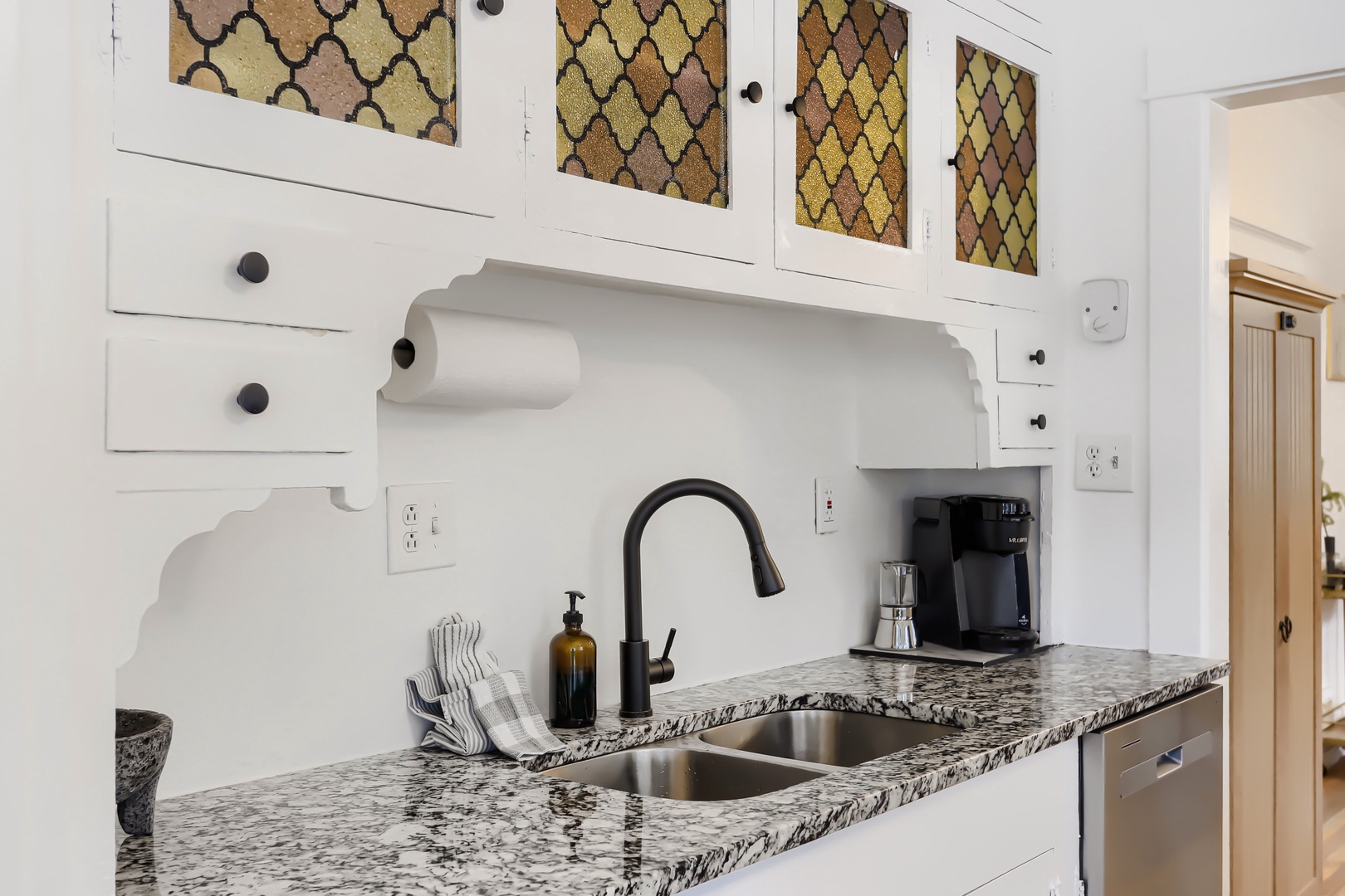 Your kitchen features elegant granite counters, stylish cabinetry with decorative glass panels, and everything you need to prepare meals during your stay.