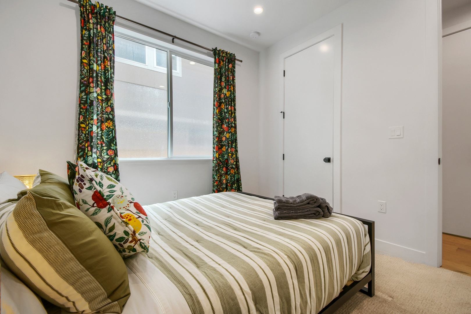 Relax in your peaceful bedroom where cheerful floral curtains frame the window and fresh towels await. Sink into the cozy striped bedding and let the vibrant details welcome you home.