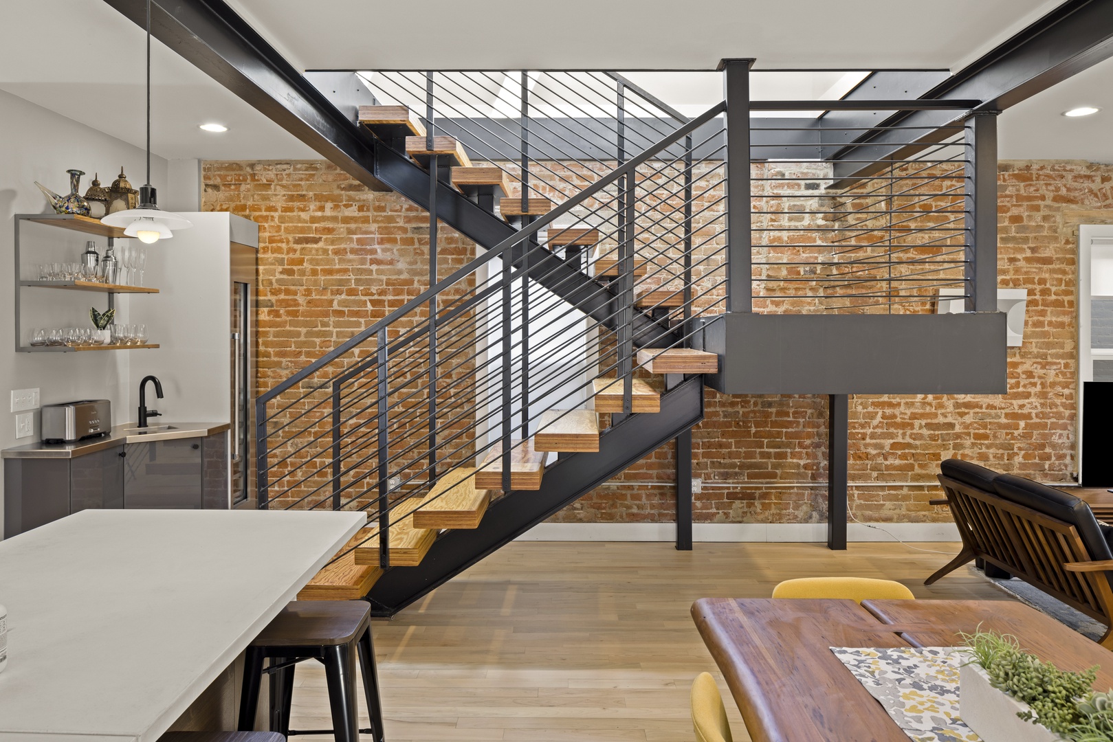Stunning industrial-modern space where exposed brick meets sleek metal stairs, creating your perfect urban retreat with open-concept living.