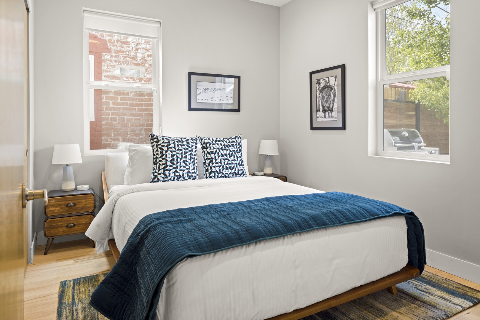 Sink into this cozy bedroom with crisp white linens and navy accents. Natural light flows through windows while thoughtful touches create your perfect retreat.