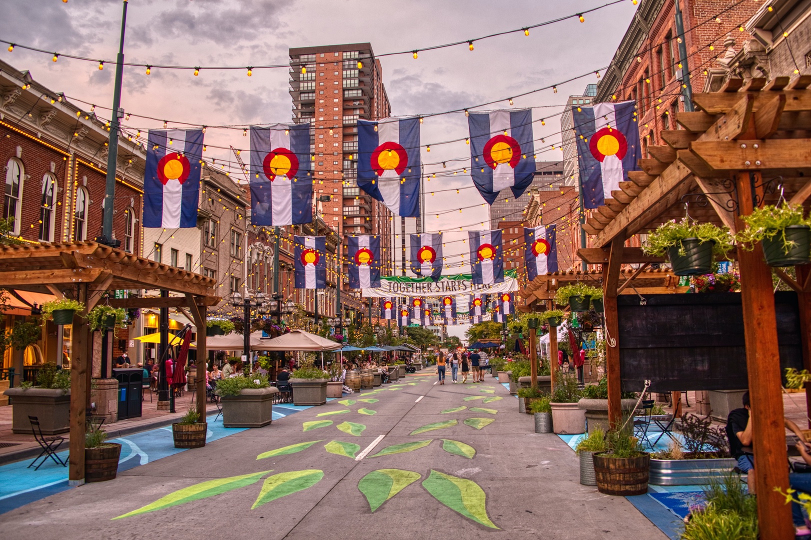 Historic downtown pedestrian mall featuring Colorado flags, local shops, and vibrant community atmosphere perfect for evening strolls.