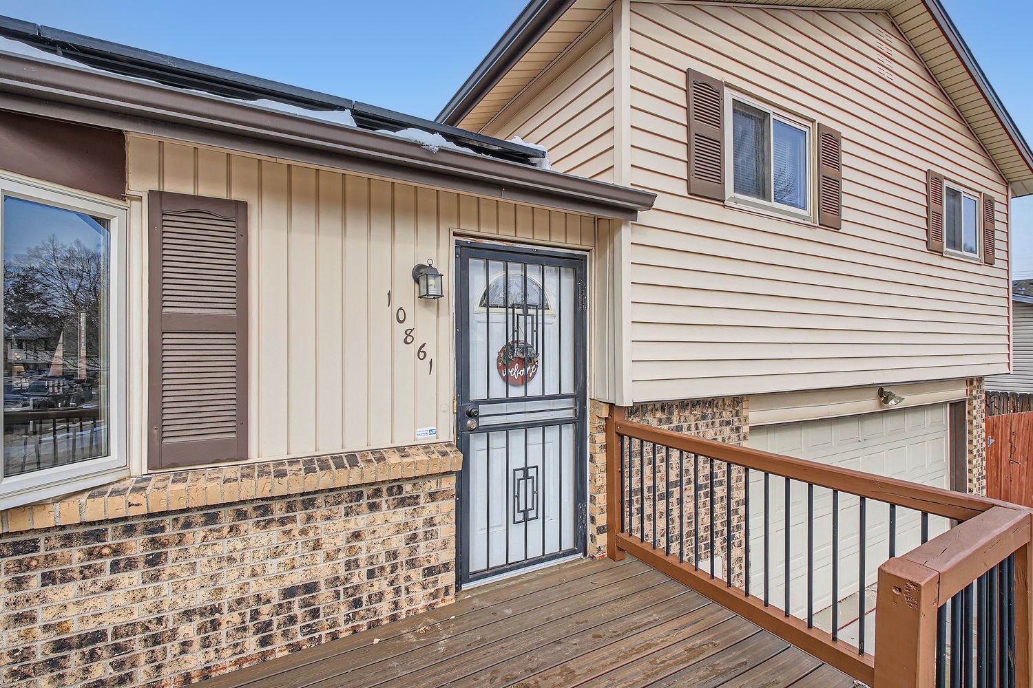The property entrance features a welcoming front deck and distinctive brick detailing, located at 10861 in a quiet residential neighborhood.