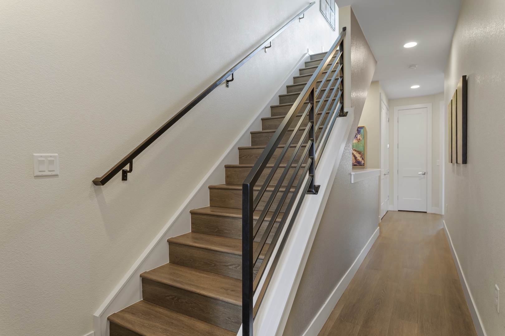 Ascend the sleek wooden staircase to your private retreat, with modern railings and warm lighting guiding your way upstairs.