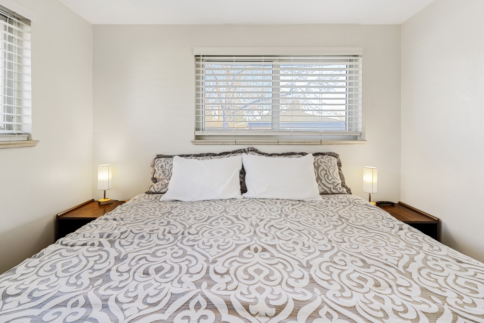 Drift off peacefully in your cozy bedroom, where soft morning light filters through elegant blinds and plush bedding awaits.