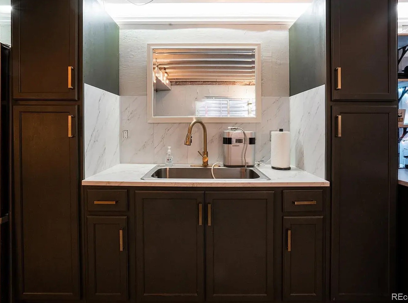Your elegant kitchen features rich dark cabinetry, marble backsplash, and gleaming brass fixtures - perfect for preparing memorable meals.