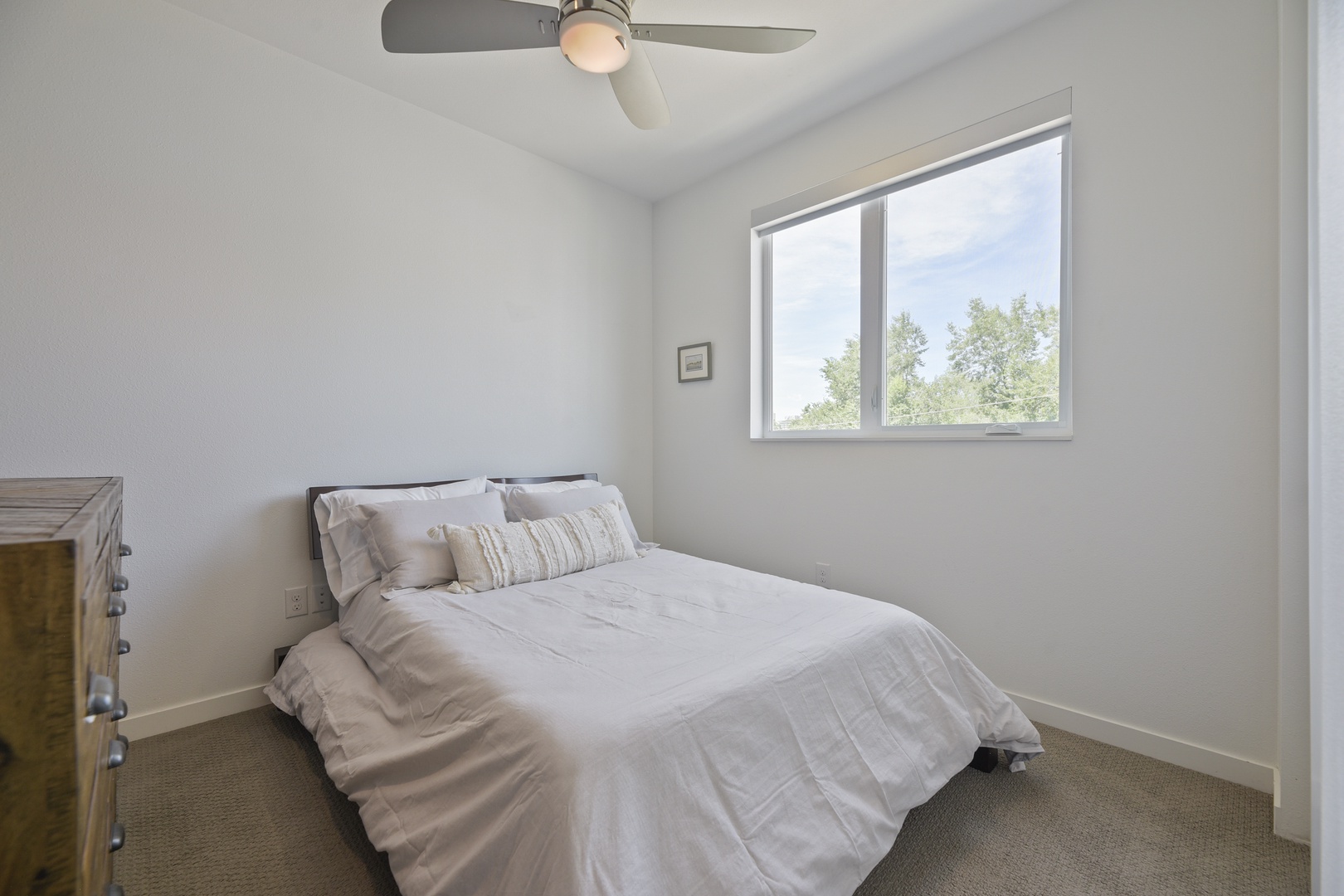 Drift off in this serene bedroom where soft linens and a gentle ceiling fan promise restful nights, while bright natural light and peaceful treetop views greet you each morning.