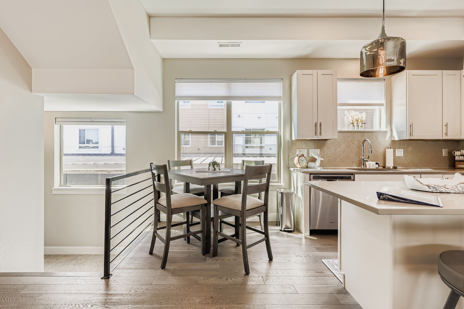 Step into your bright, modern kitchen where white cabinetry and warm tile backsplash create an inviting space for cooking and casual meals at the breakfast table.