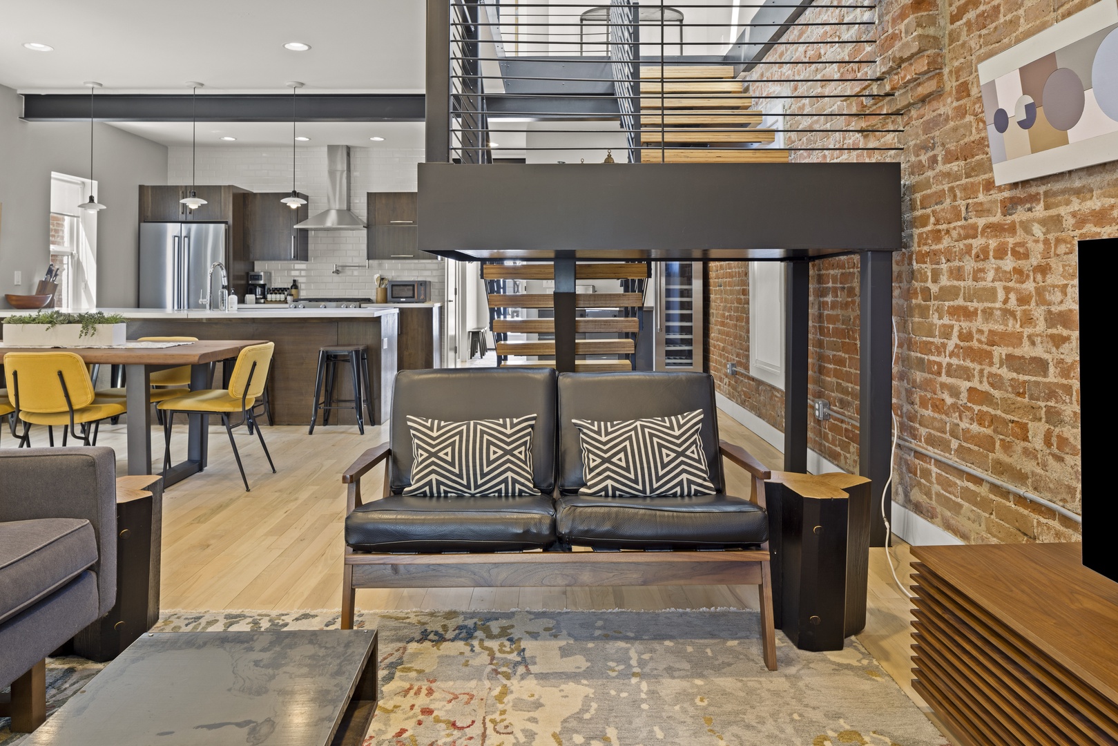 Your modern loft features exposed brick walls, sleek furniture, and an open-concept design connecting living and kitchen spaces seamlessly.