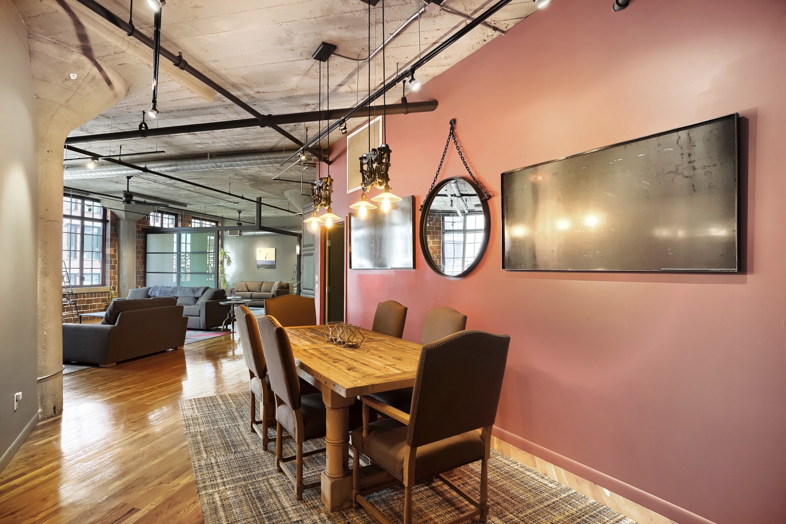 You'll love gathering around this stylish dining table under warm pendant lights, with an open-concept living space flowing seamlessly beyond. The exposed beams and rich wood floors create a loft-like urban charm perfect for your stay.