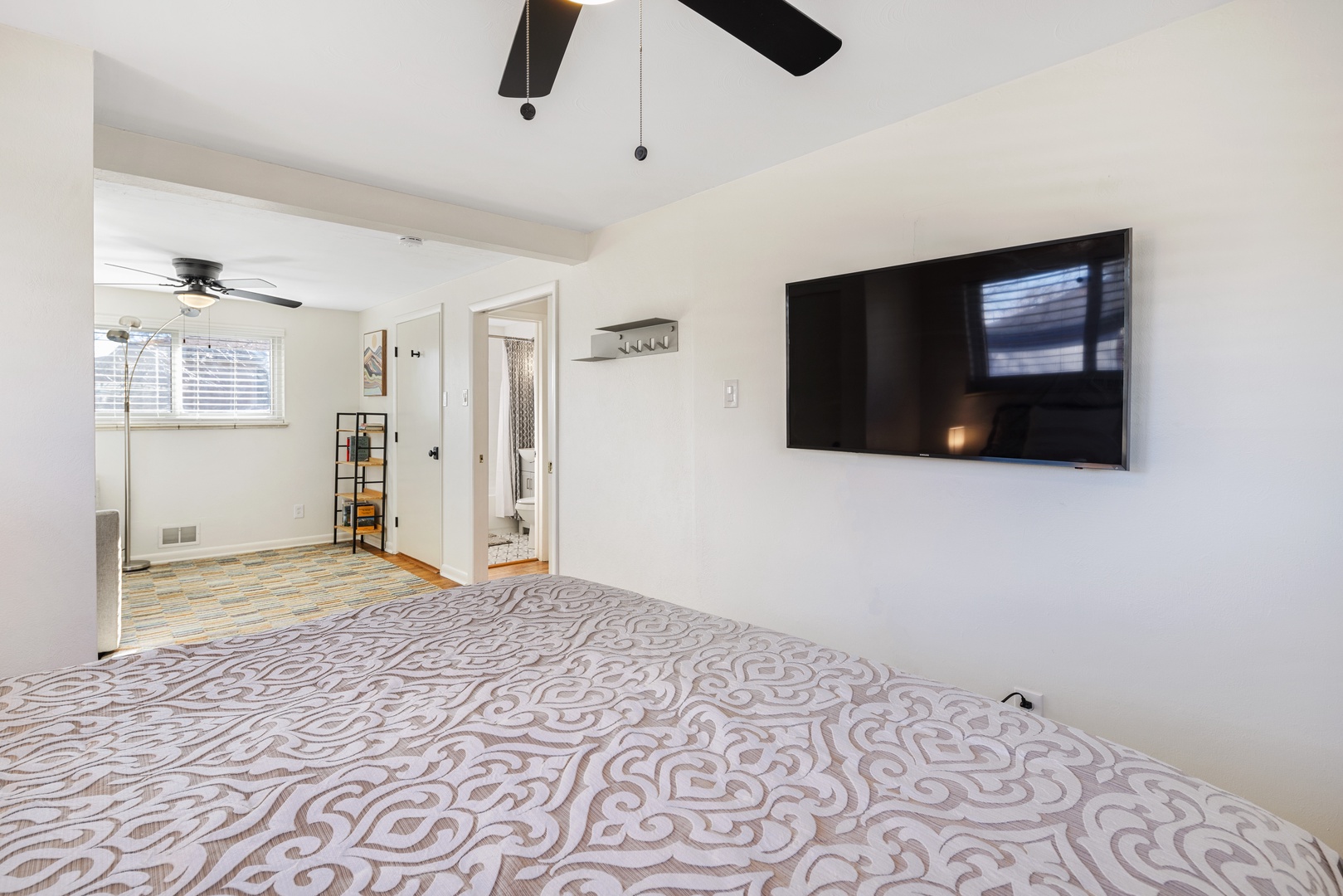 Relax in your spacious bedroom with ceiling fan, mounted TV, and private bathroom access for ultimate comfort.