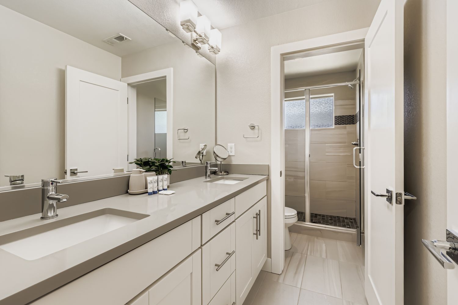 Start your day in this sleek, modern bathroom featuring dual vanities with ample counter space, soft lighting, and a spacious walk-in shower that feels like your personal spa retreat.