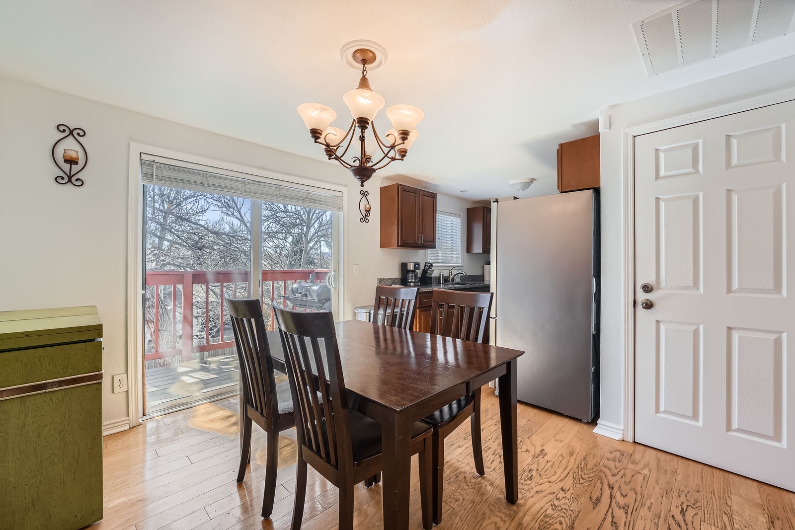 Gather around this warm dining space where your meals become memories, with elegant chandelier lighting and deck access for fresh air.