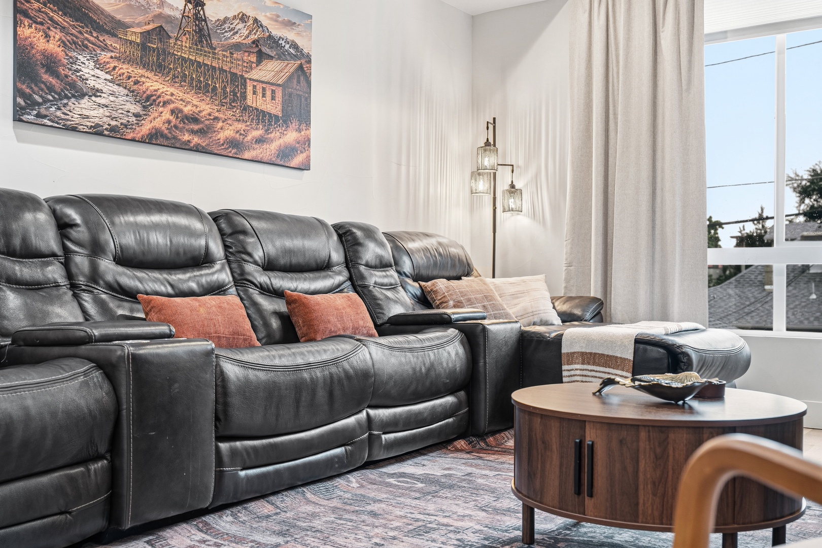 Sink into plush leather seating and unwind in your spacious living room, where natural light streams through floor-to-ceiling windows and thoughtful decor invites relaxation.