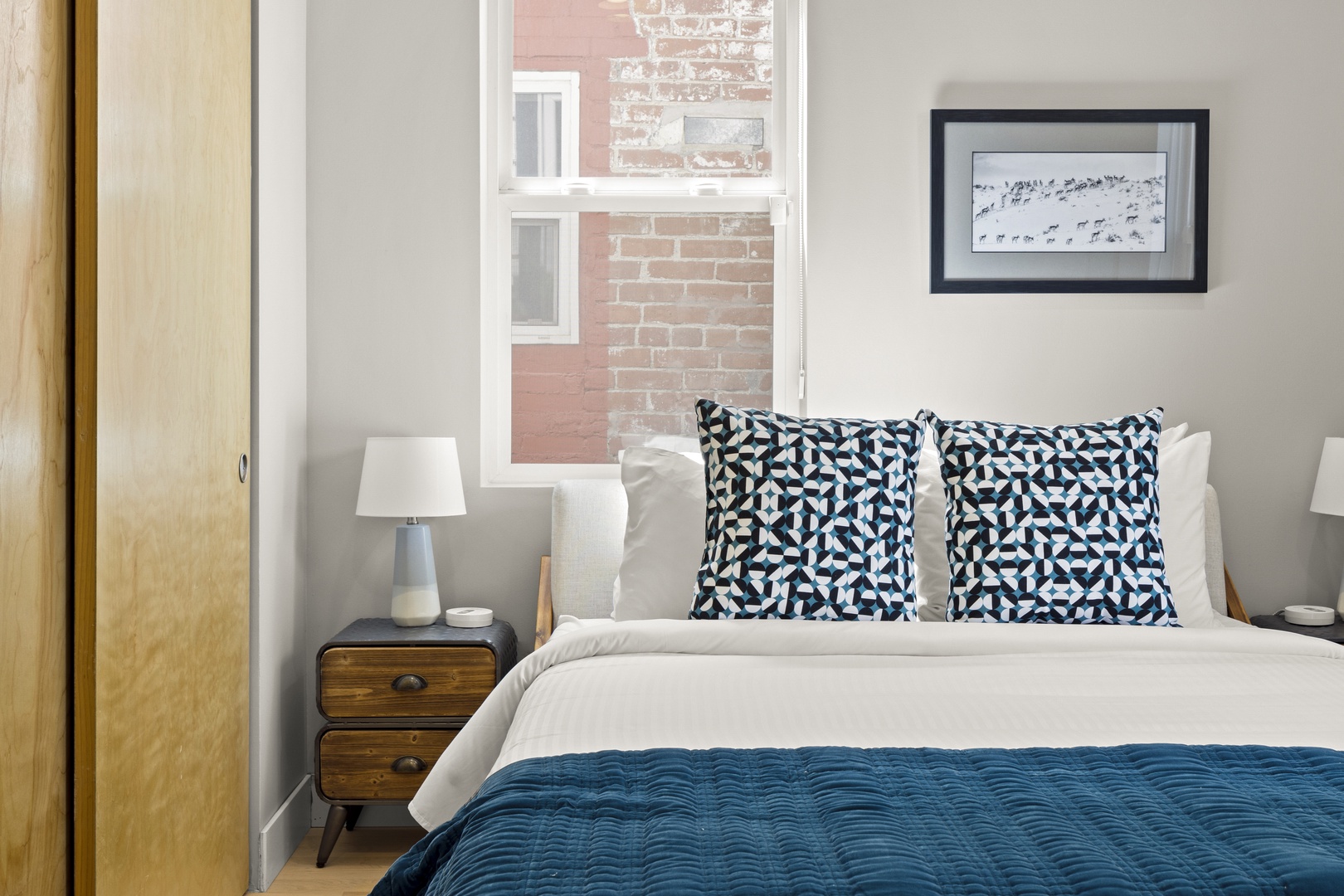 Sink into crisp linens and geometric pillows in your bright bedroom, where natural light flows through large windows.