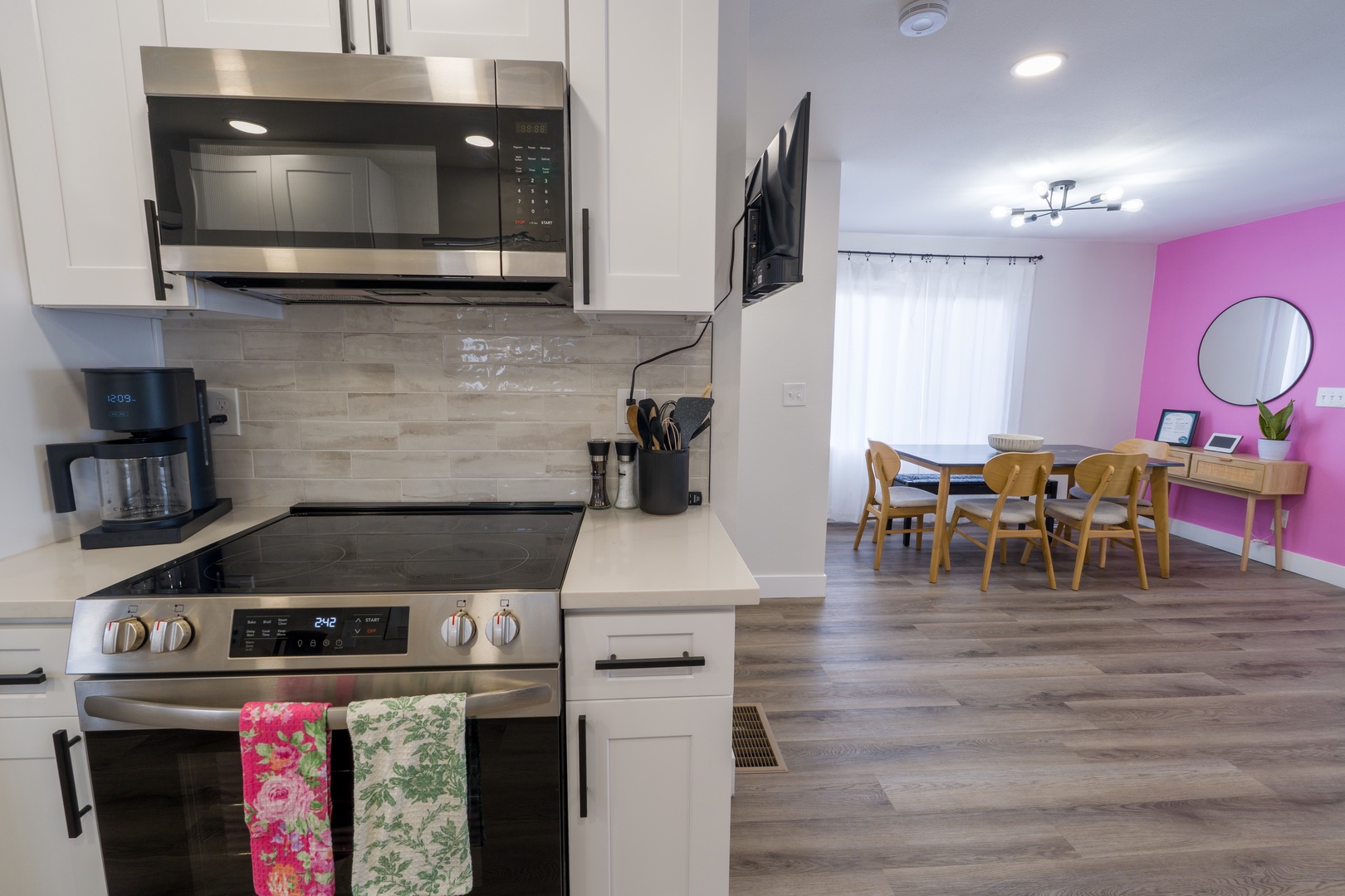 Your modern kitchen features stainless appliances and flows into a bright dining space with cheerful pink accent wall.