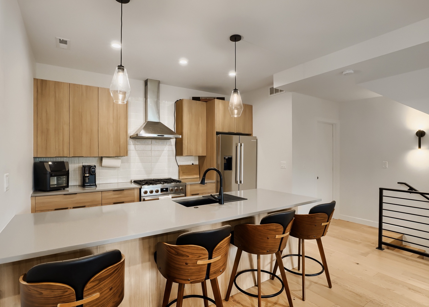 Gather around this sleek kitchen island for your morning coffee or casual meals. Modern appliances and warm wood cabinetry create a stylish space for cooking and connecting.