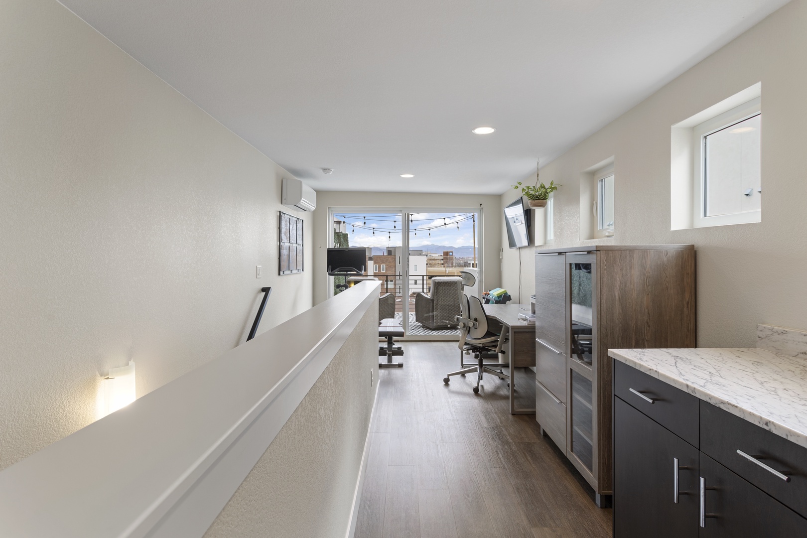 Step into your modern sanctuary with sleek kitchen, comfortable workspace, and bright windows framing outdoor string lights for cozy evenings.