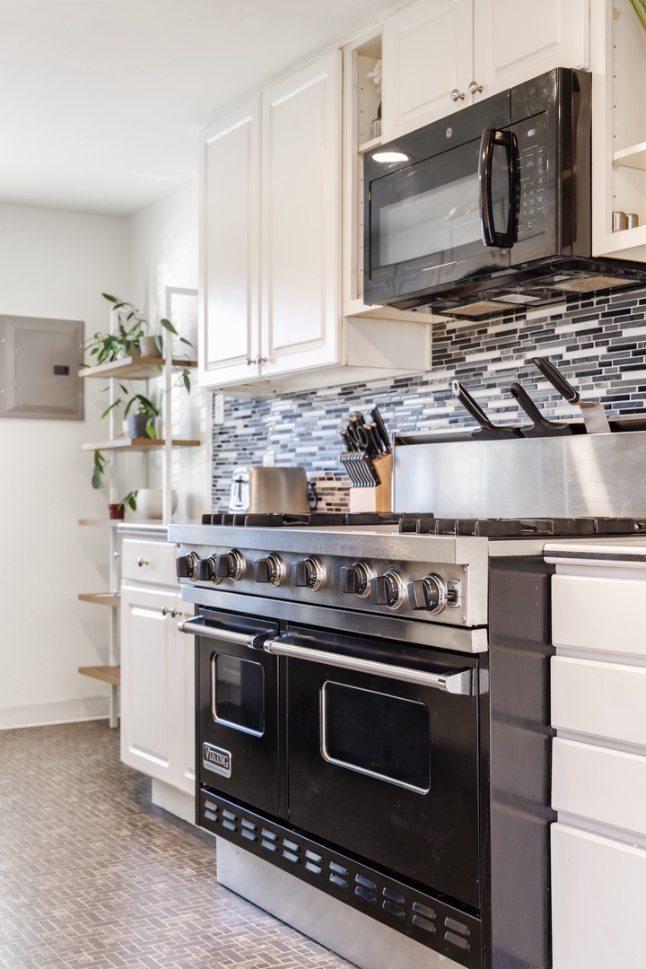 Your fully-equipped kitchen invites culinary creativity with professional-grade appliances, sleek white cabinetry, and stylish mosaic backsplash creating the perfect cooking sanctuary.