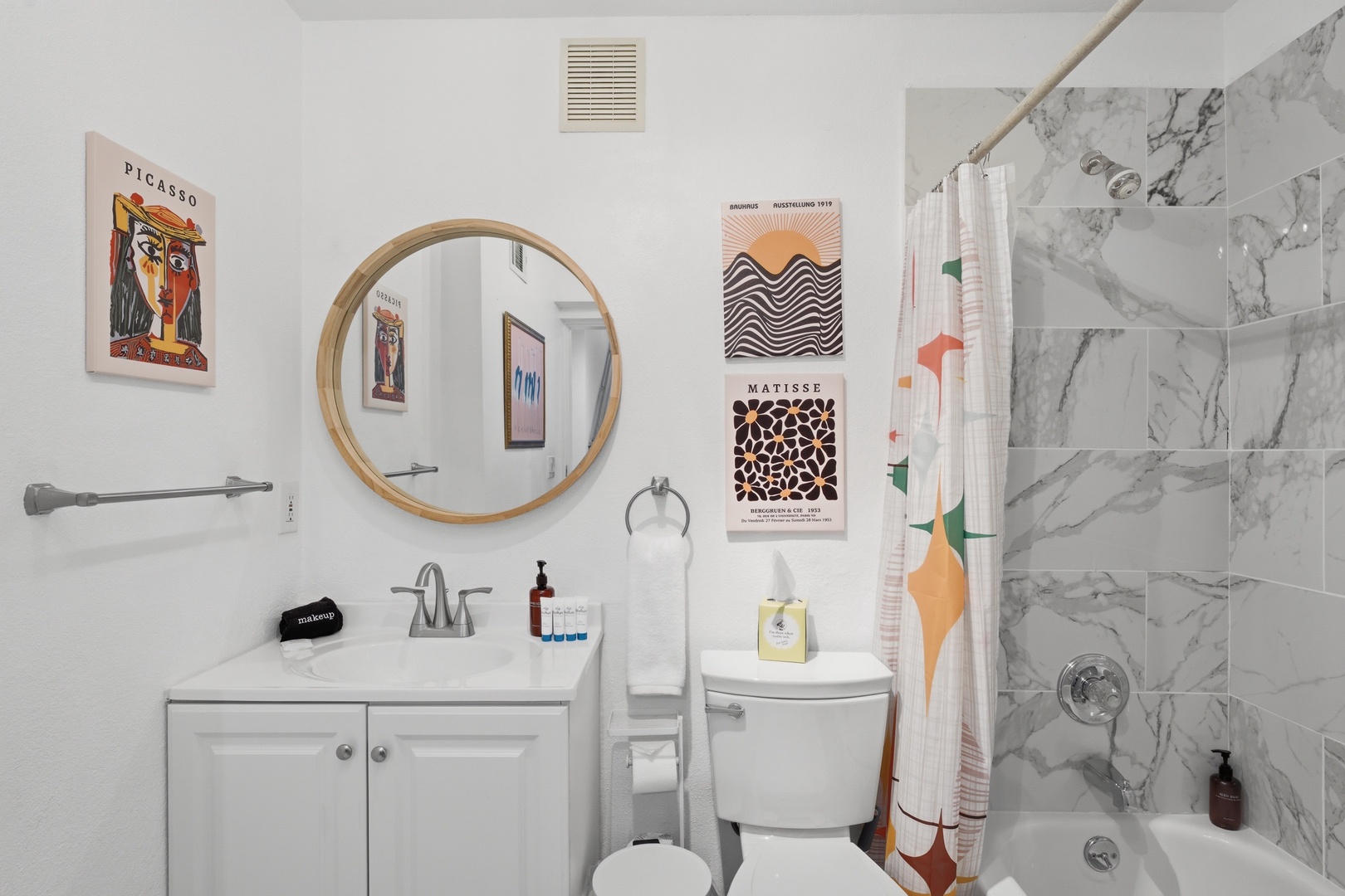 Step into this bright, artfully styled bathroom where clean lines meet personality. The large round mirror, modern fixtures, and marble-look tub-shower combo are yours to enjoy after each day's adventure.