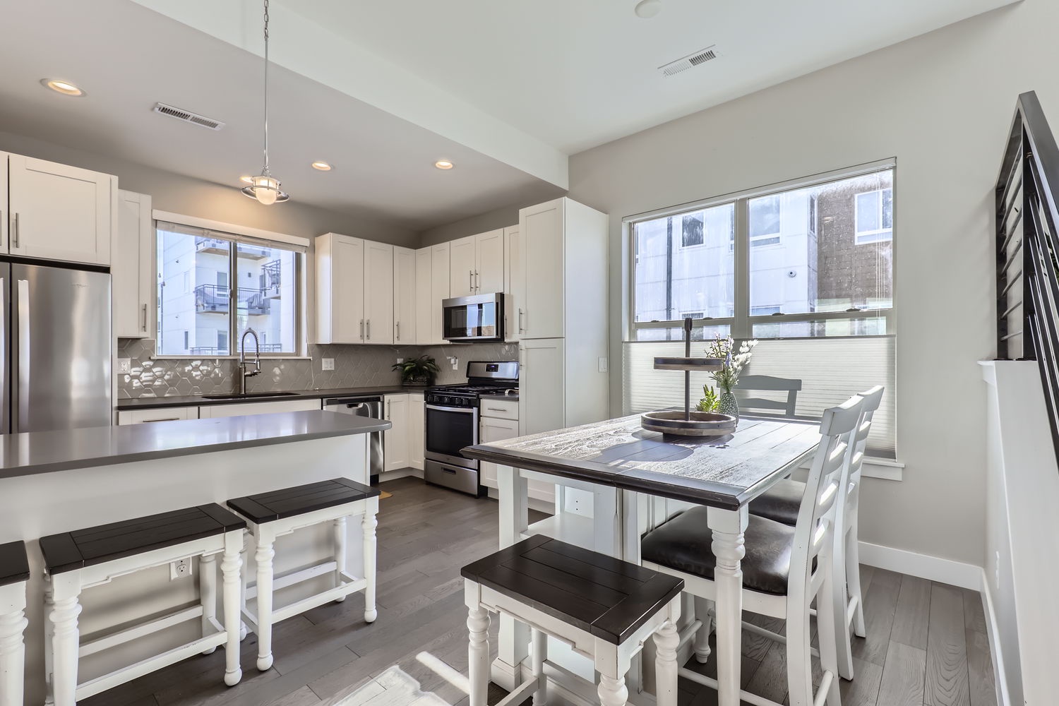 Cook and gather around the elegant island and dining table in this bright kitchen. Gleaming stainless-steel appliances, crisp white cabinetry, and abundant natural light create the perfect setting for your home-cooked meals.