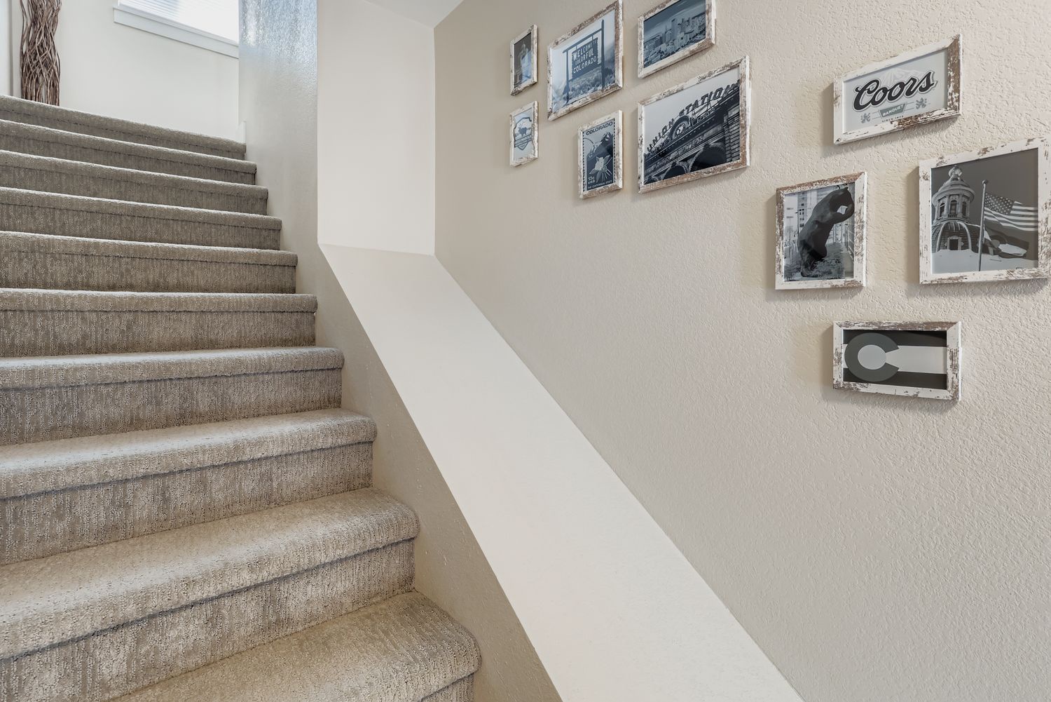 Ascend the carpeted stairway adorned with vintage photo frames, a thoughtful touch that tells the story of this charming home's character and history.