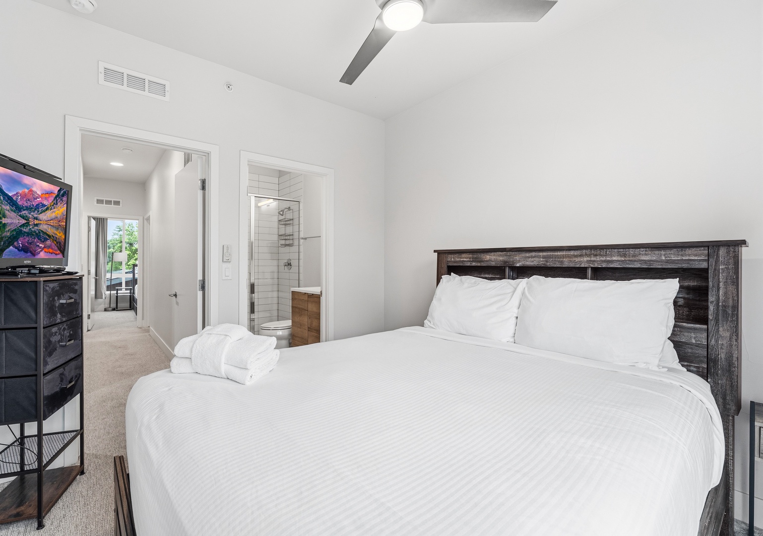 Sink into crisp, cloud-white linens and unwind in your serene bedroom retreat, complete with a modern ensuite and sleek ceiling fan for comfort.
