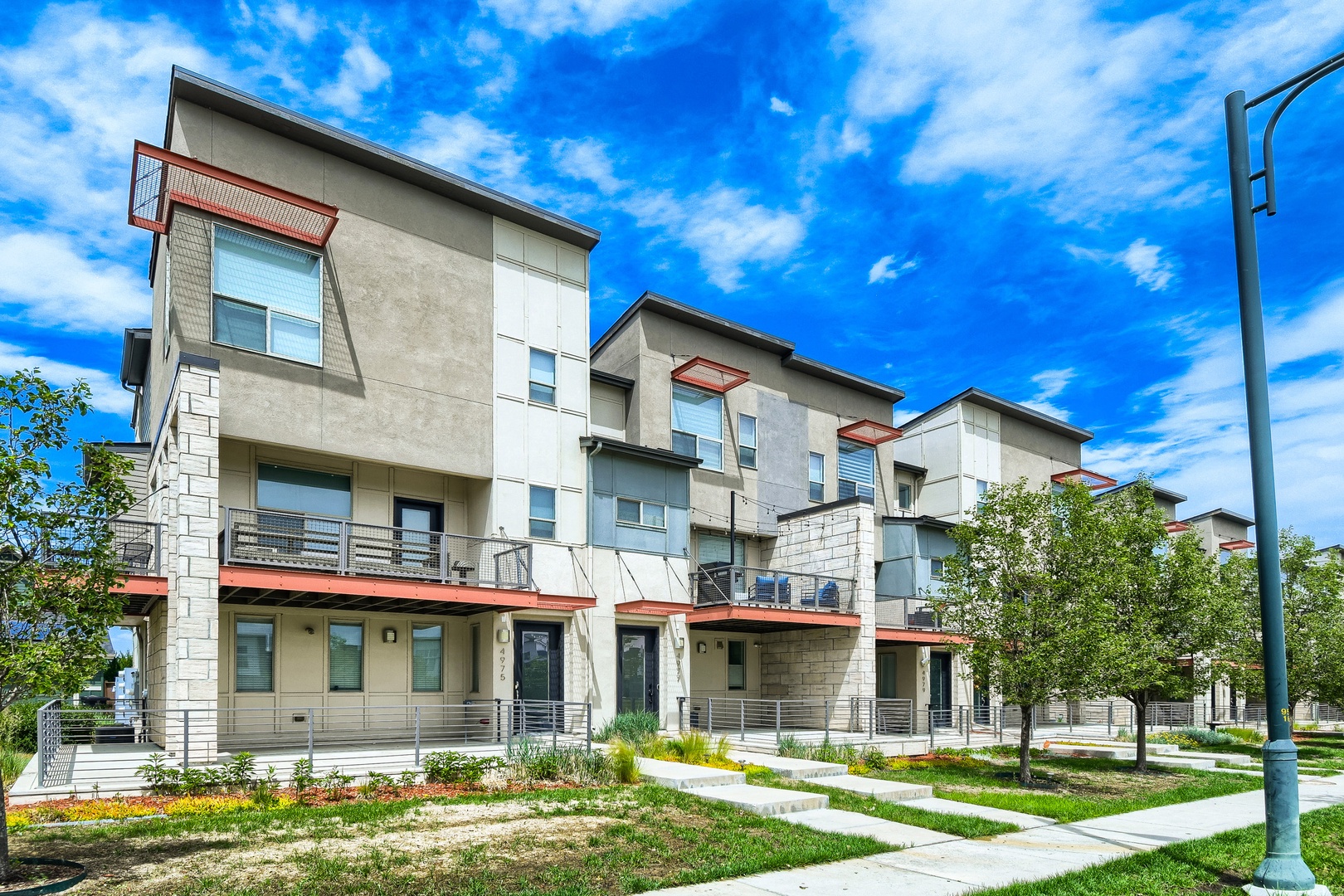 Modern property building featuring contemporary architecture with multiple levels, private balconies, and well-maintained landscaping in a residential neighborhood setting.