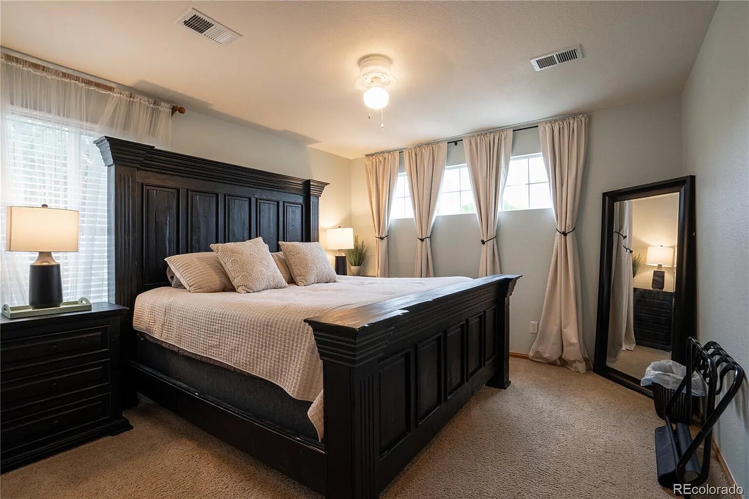 Sink into luxury in your master bedroom with rich dark furniture and soft linens, complete with natural light streaming through elegant curtains.