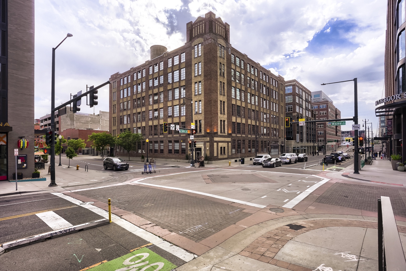 Historic brick building marks the property location at a prominent street corner in a vibrant urban neighborhood with shops and restaurants nearby.