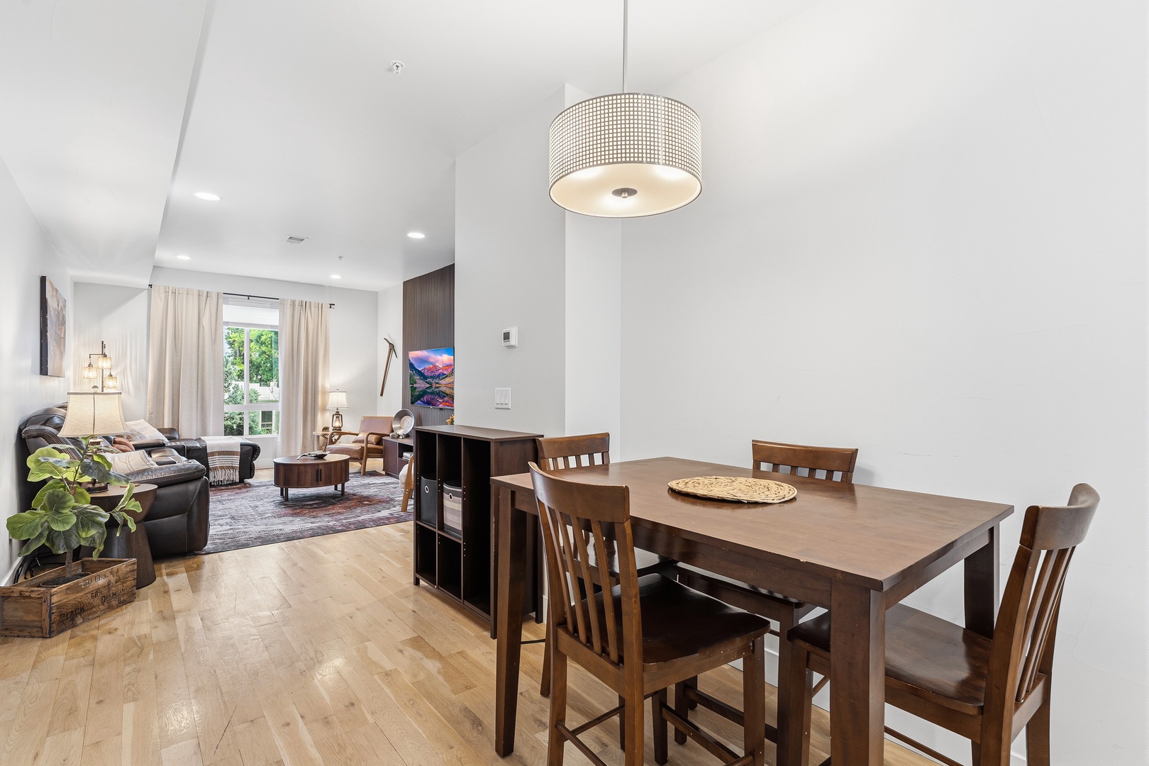 Step into this bright, open-concept space where natural light fills your living and dining areas. Enjoy meals at the wood table, then relax on the cozy couch with views of lush greenery outside.