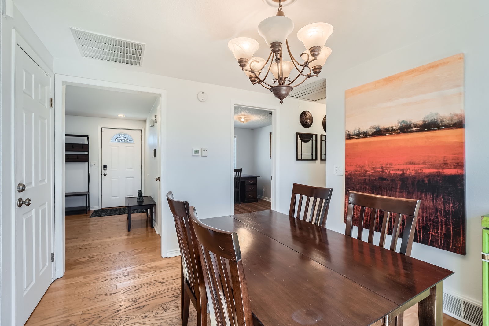 Gather around your elegant dining table for memorable meals under warm chandelier light and captivating artwork.