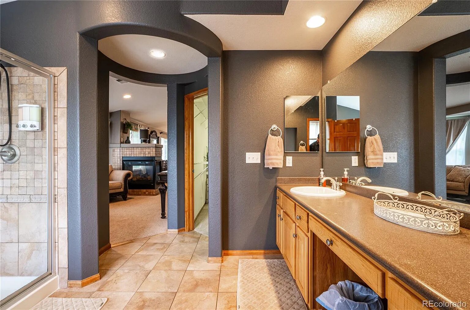 Step into your spacious master bathroom featuring dual vanities and warm wood cabinetry for your morning routine.