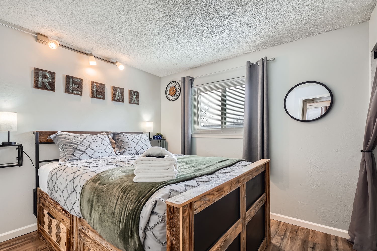 Slip into your peaceful retreat, where thoughtful touches like soft lighting and fresh towels await. The rustic wood bed frame and inviting linens make this bedroom your perfect spot to unwind after exploring.