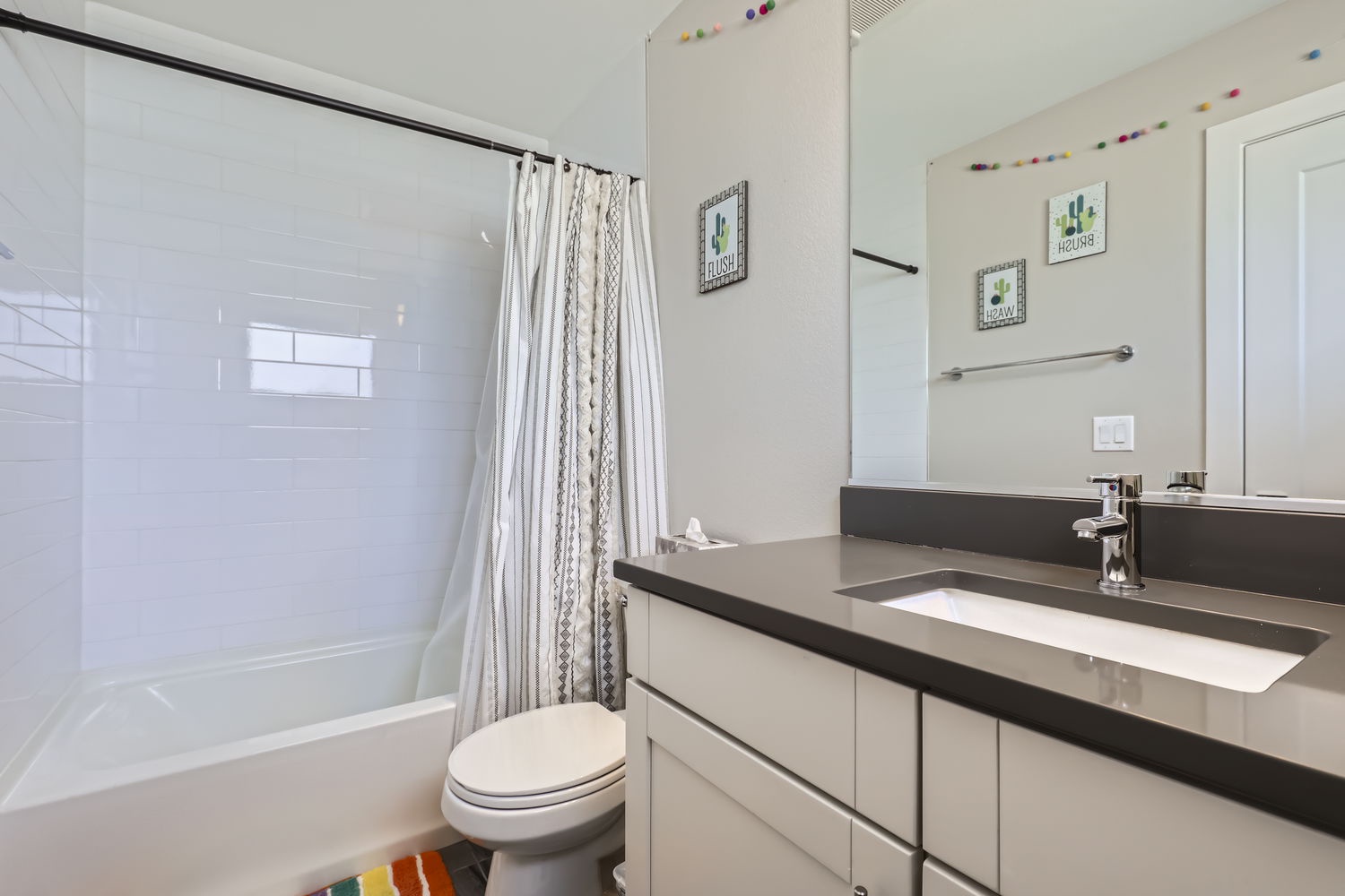 Step into your clean, modern bathroom with sleek countertops, a refreshing tub-shower combo, and cheerful touches that make getting ready feel effortless.