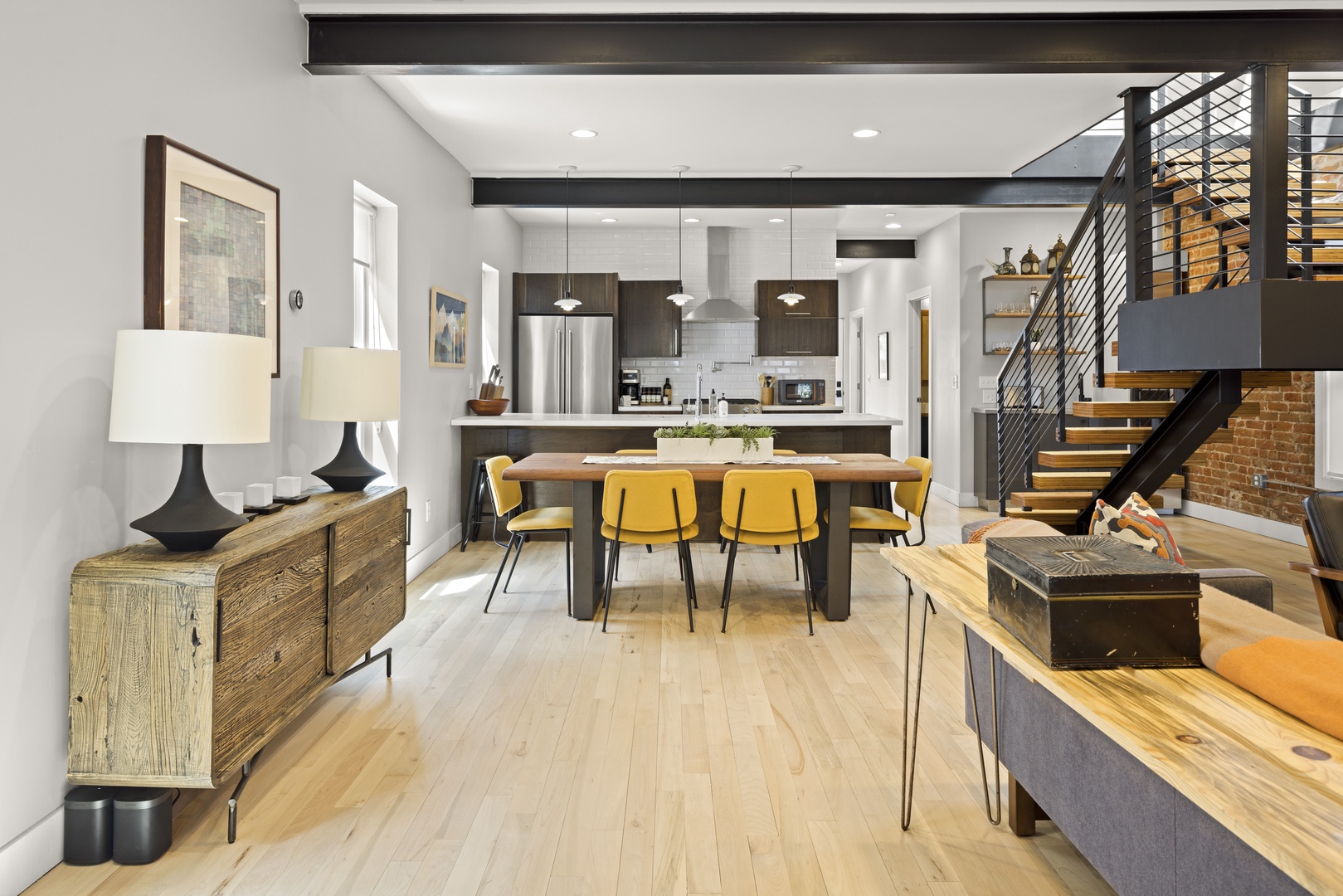 Your open-concept living space flows seamlessly from kitchen to dining, with warm wood floors and modern industrial touches creating the perfect atmosphere.