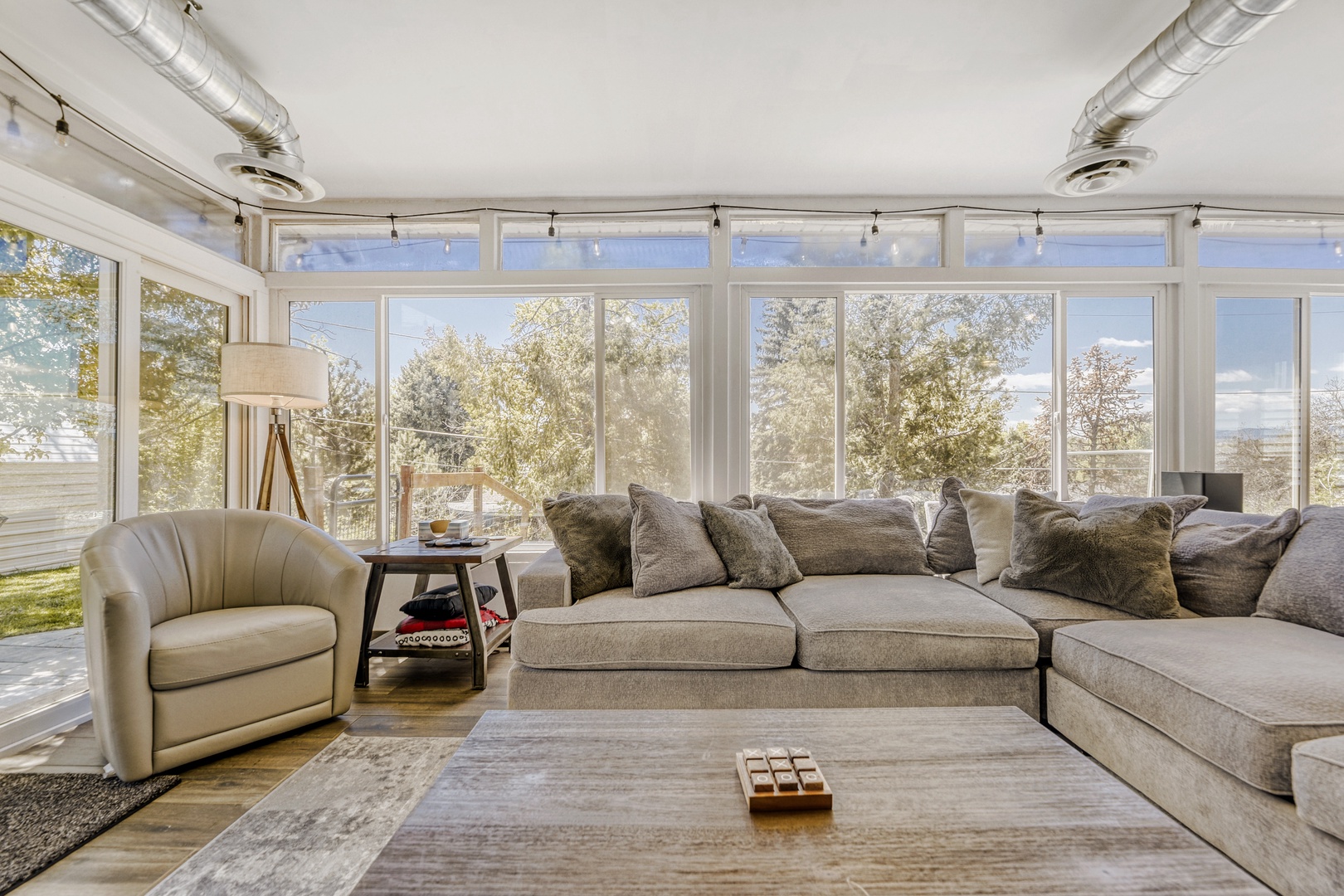 Settle into your sunlit living room, where floor-to-ceiling windows frame serene garden views. Sink into plush seating and let natural light fill your peaceful retreat.