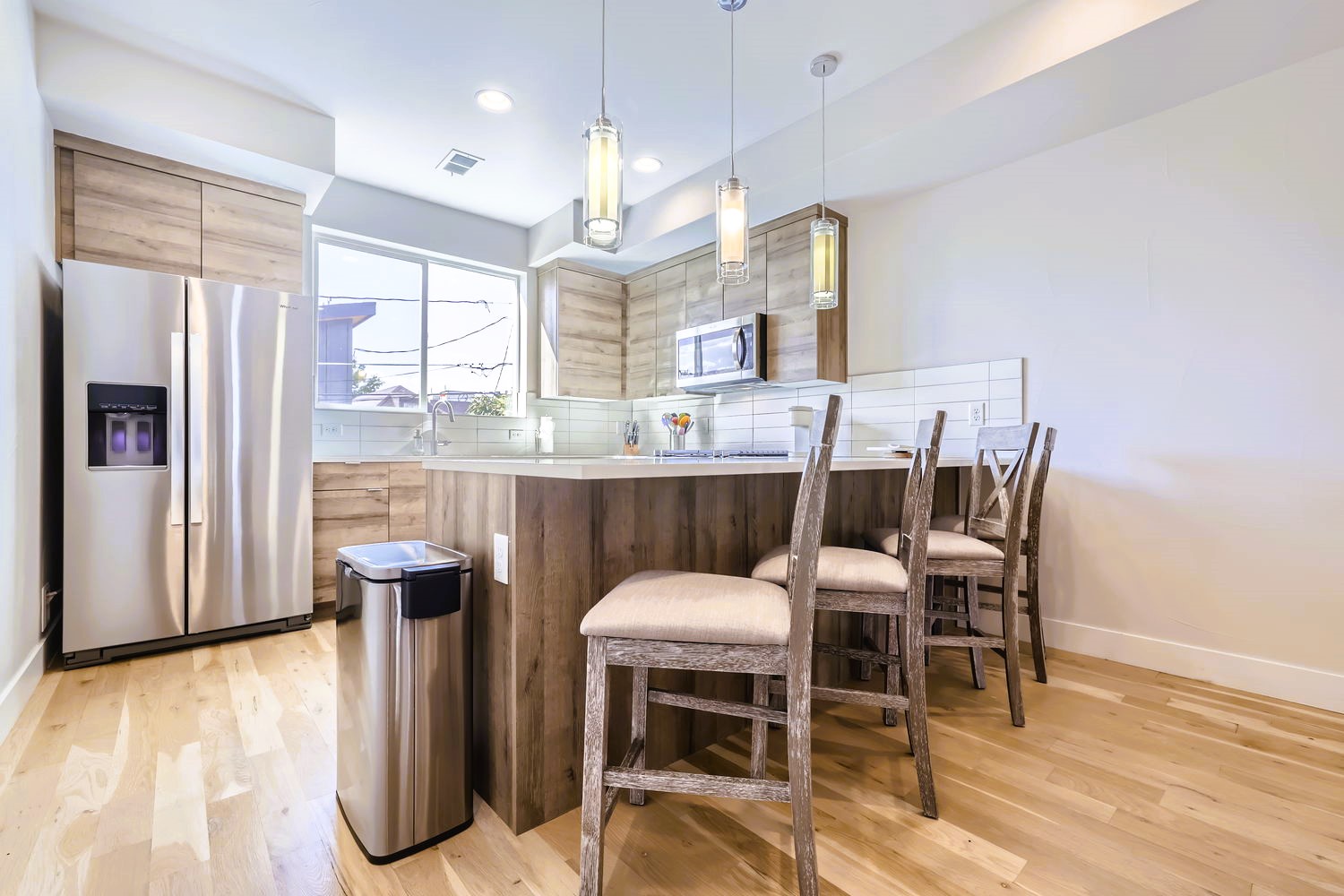 Cook memorable meals in this modern kitchen with sleek appliances, breakfast bar seating, and warm wood finishes.