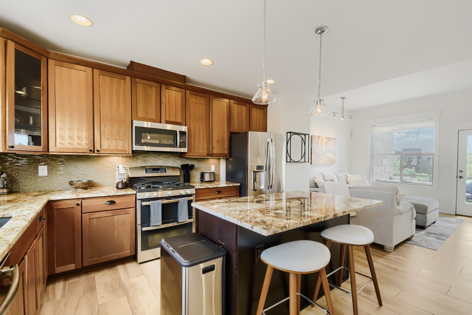Step into your open-concept kitchen and living space, where warm wood cabinetry, granite countertops, and modern stainless appliances invite you to cook, dine, and unwind together.