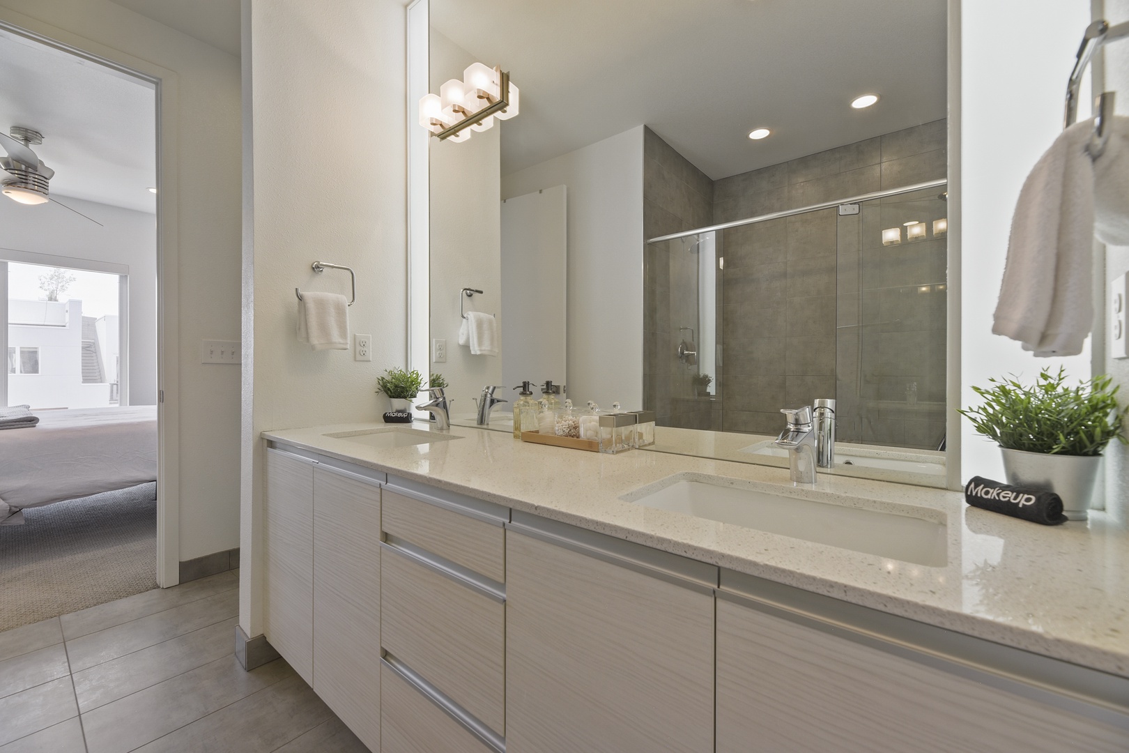Freshen up at your spacious dual-sink vanity with sleek quartz countertops, modern fixtures, and a glass-enclosed walk-in shower. Soft lighting and calming neutrals invite relaxation.